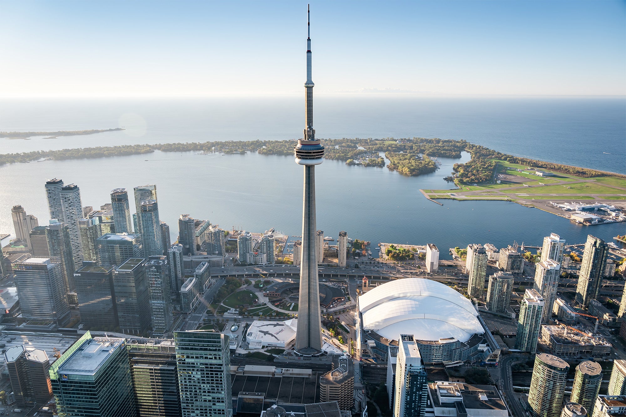 an aerial photo of the waterfront showing the CN Tower, buildings, and the Toronto Islands