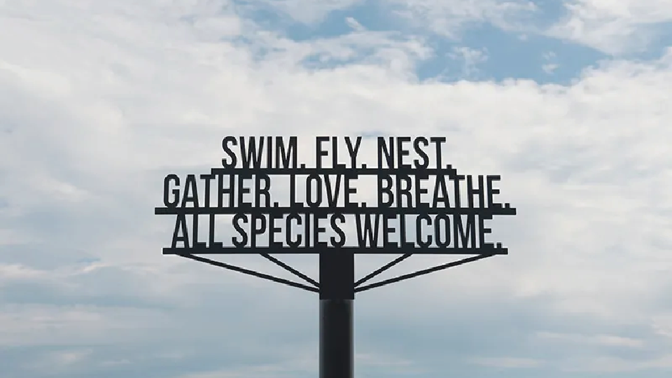 metal sign that reads: swim. fly. nest. gather. love. breathe. all species welcome.