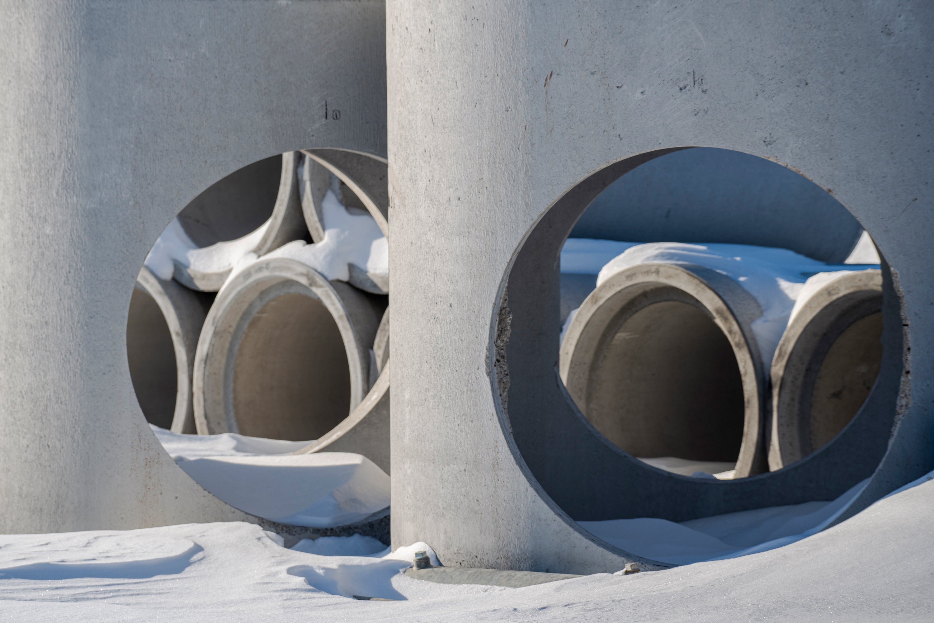 Cement pipes stacked up in a construction site in snow.