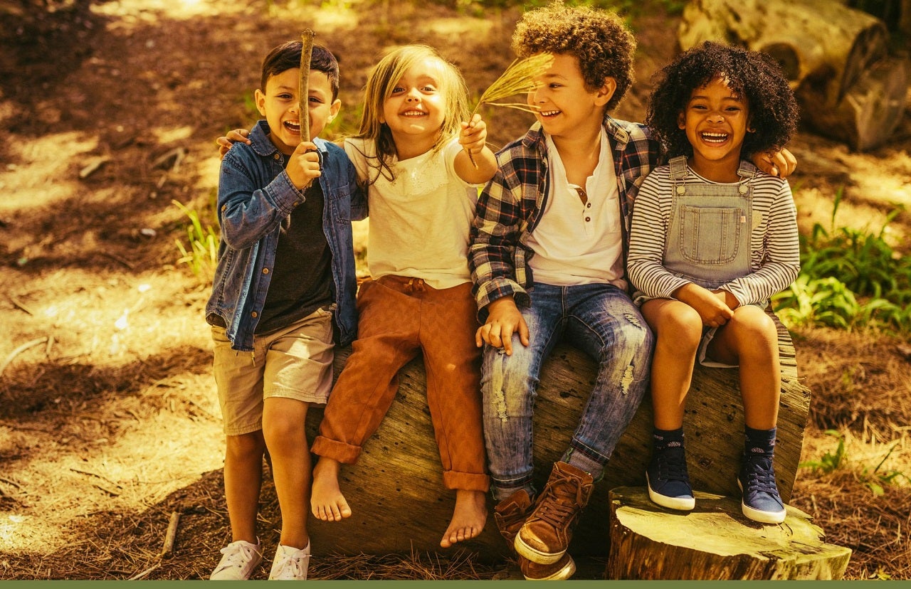 four children sitting on large rock