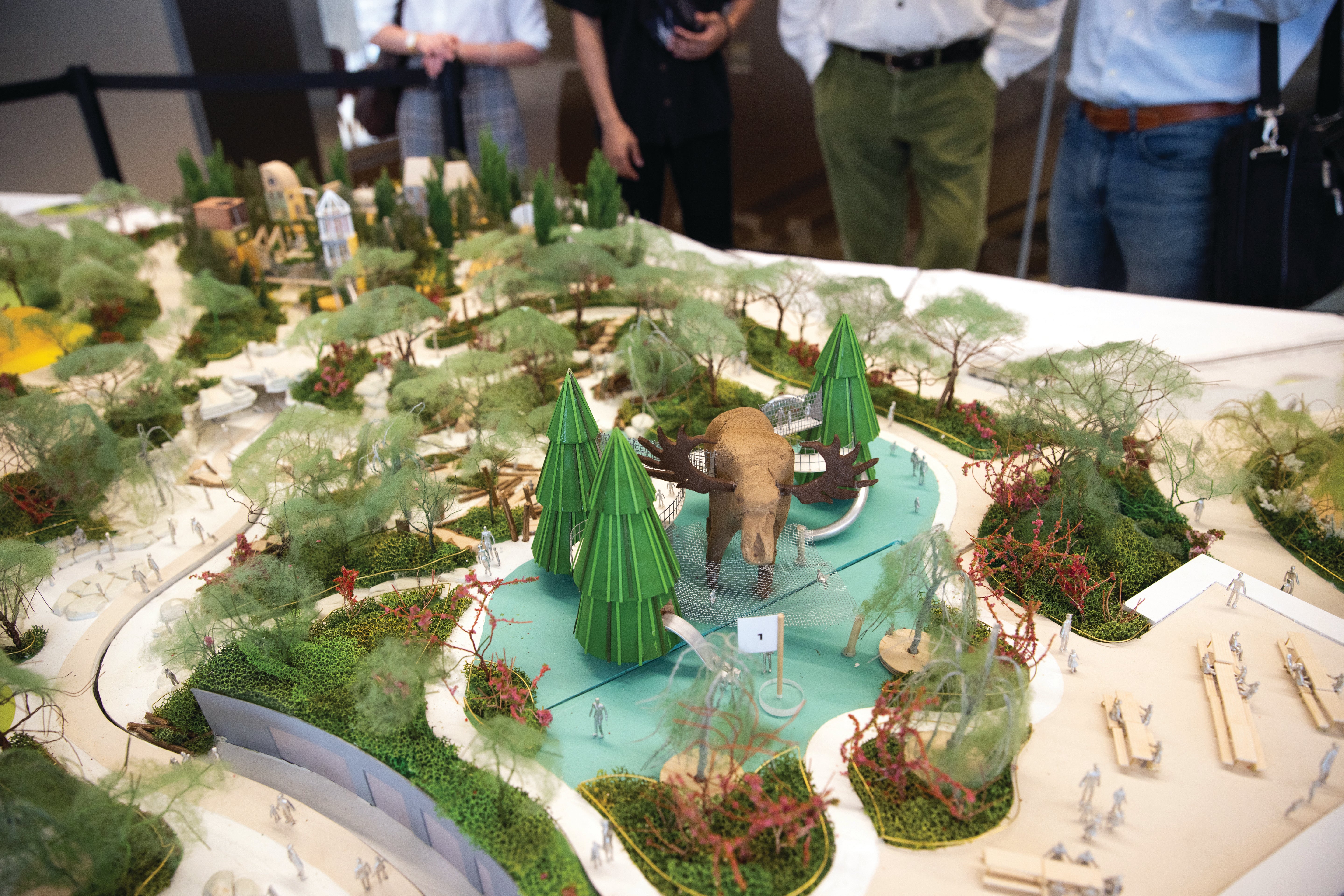 A model of a park displaying gardens, trails and a large moose in the middle.