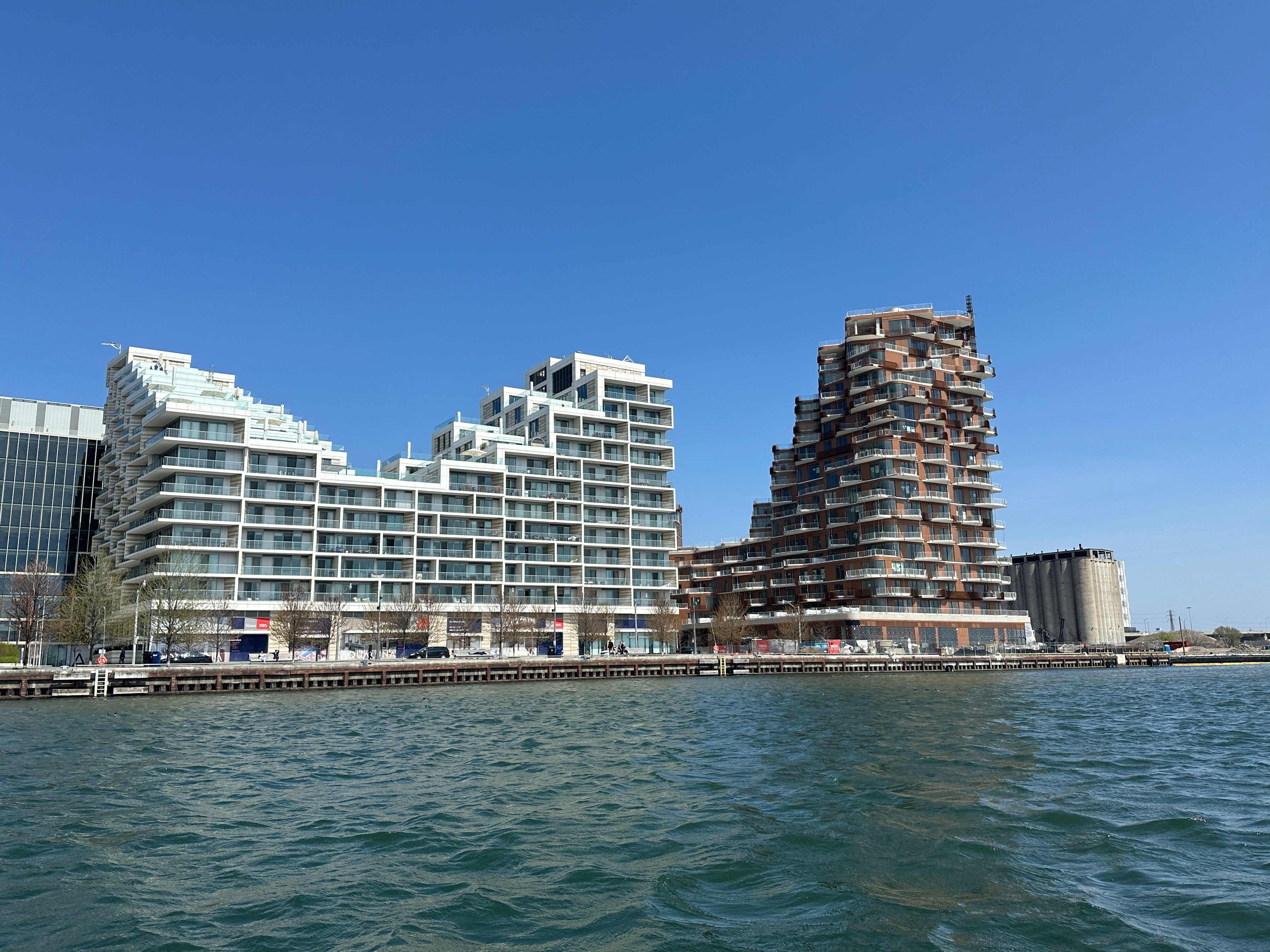 A V shaped building on Toronto's waterfront, clicked from afar with water in the front and blue sky in the background.