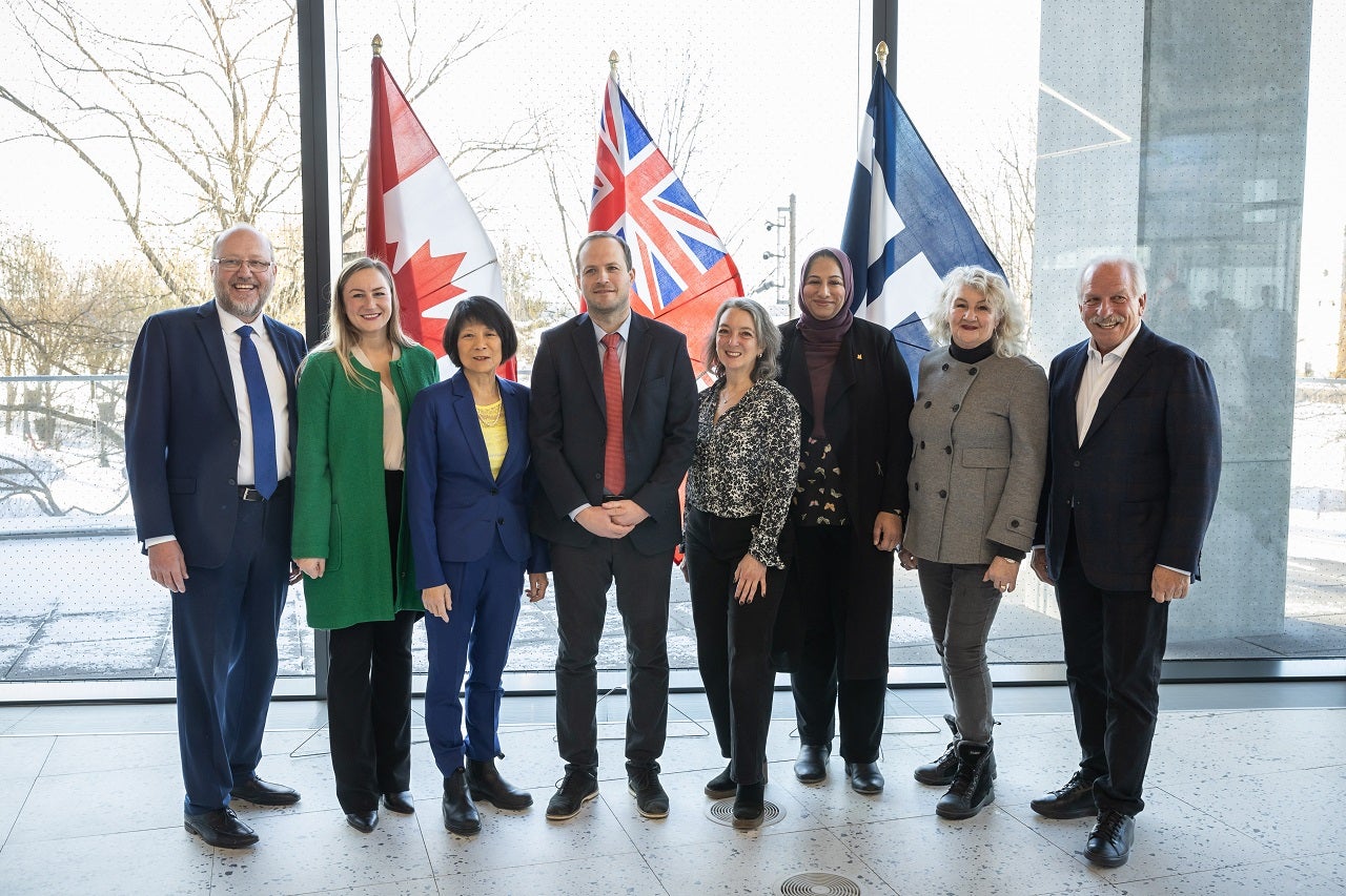 Tri-government officials and Waterfront Toronto pose in front of the Canada, Ontario and Toronto flags.