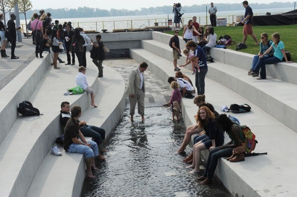 people sitting along a water channel and wading in the water