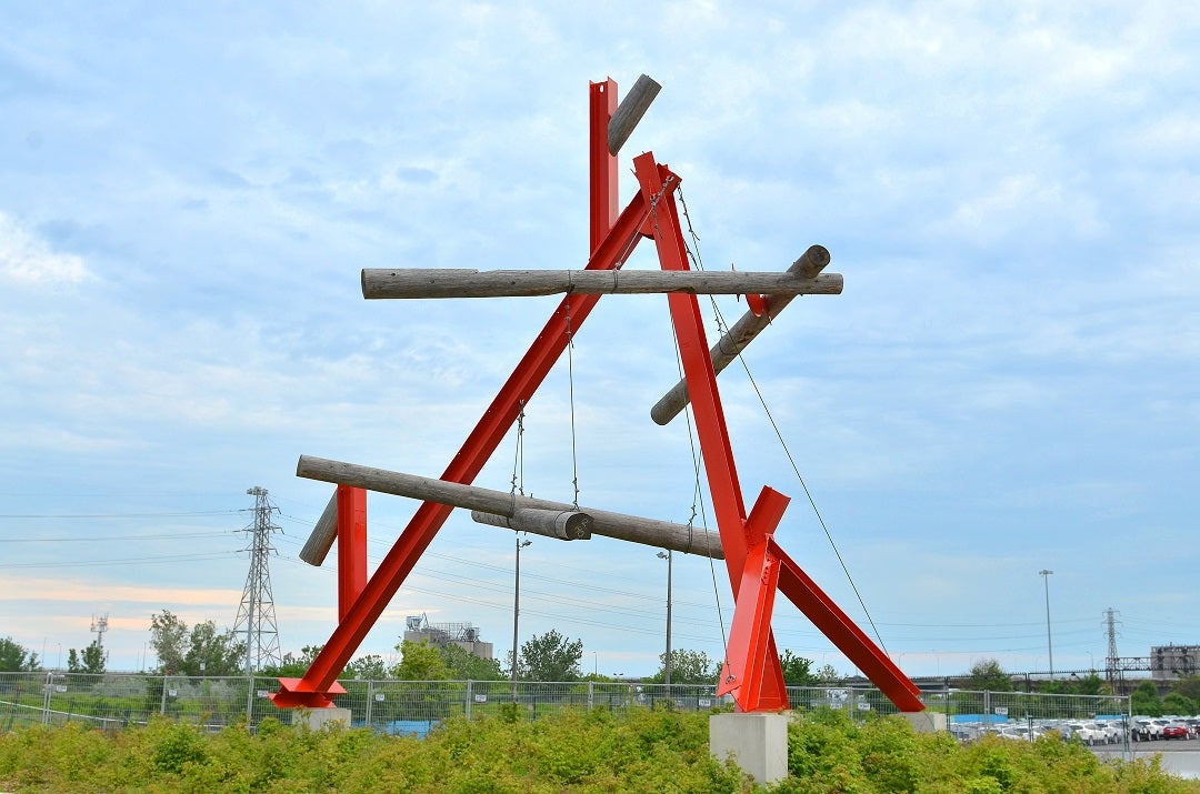 A large red public art sculpture in a park