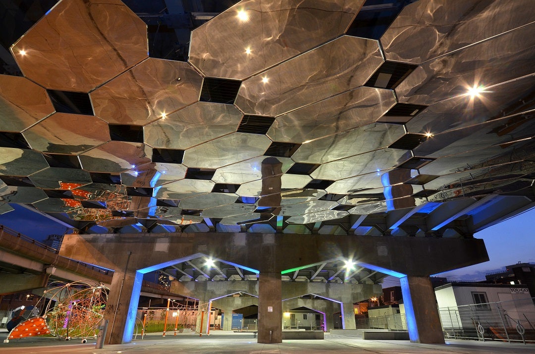 Mirrors hanging from the underside of an overpass and urban park