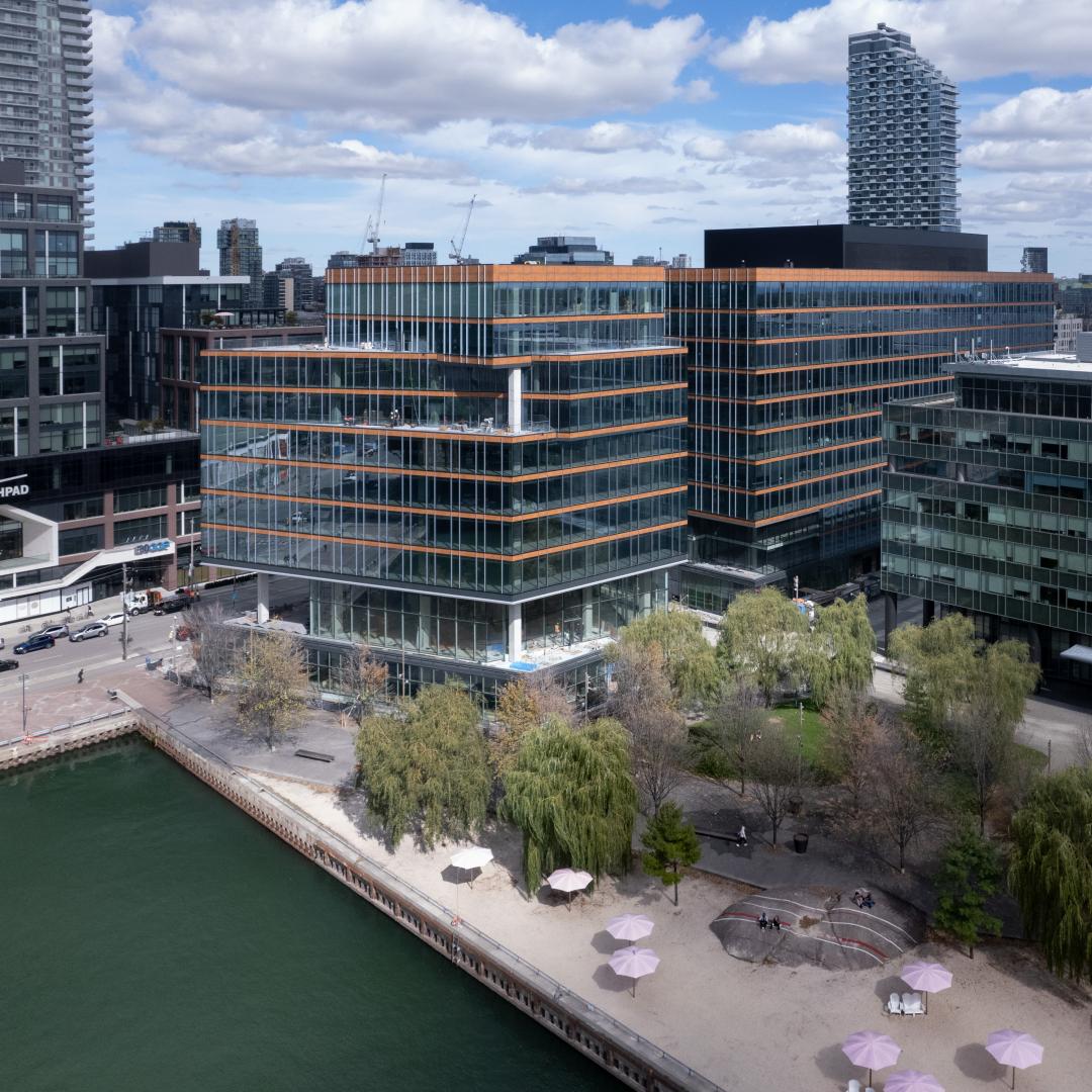 an aerial photo showing the exterior of a building next to an urban beach and Lake Ontario