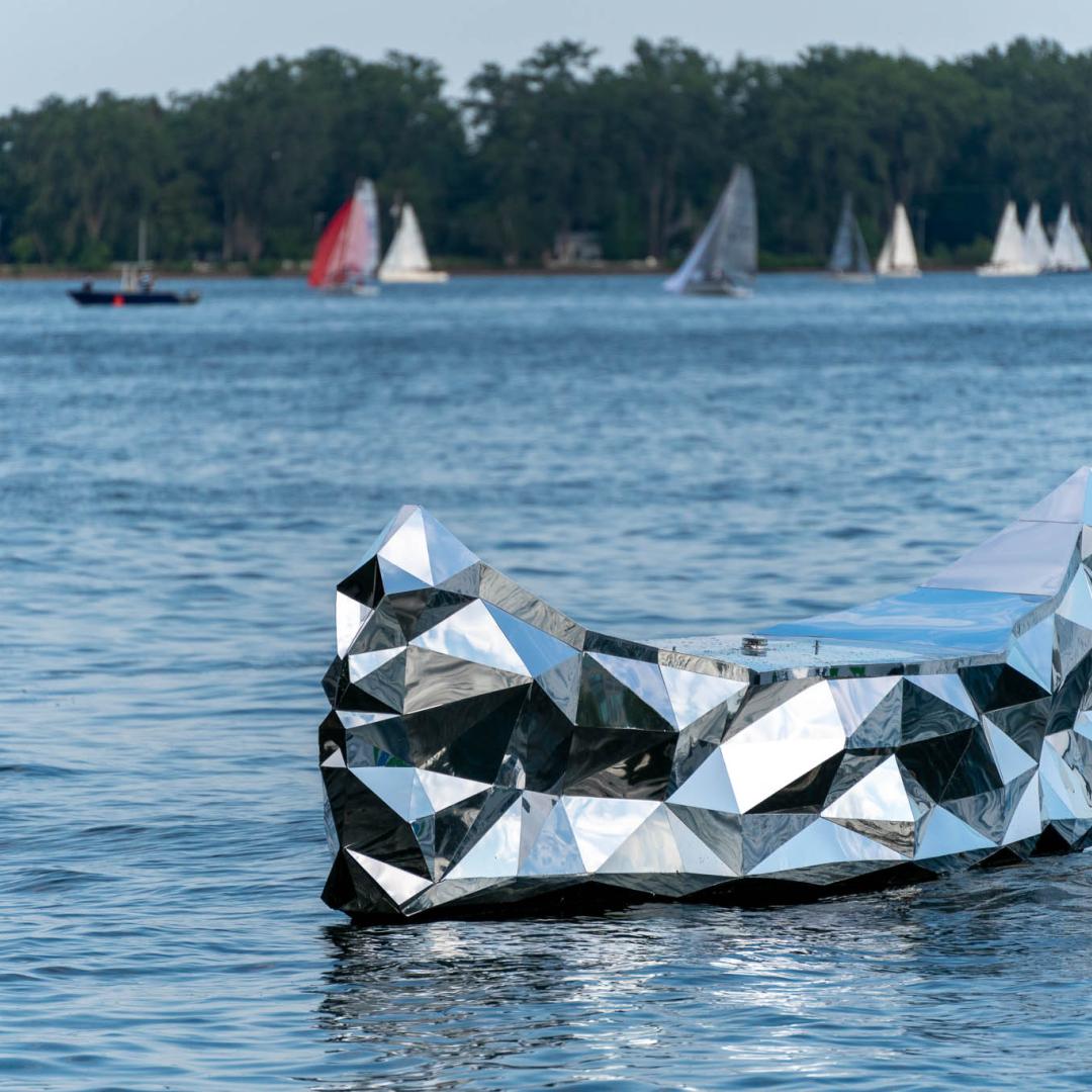 a photo of a floating public art piece that resembles a mirrored canoe in Lake Ontario 