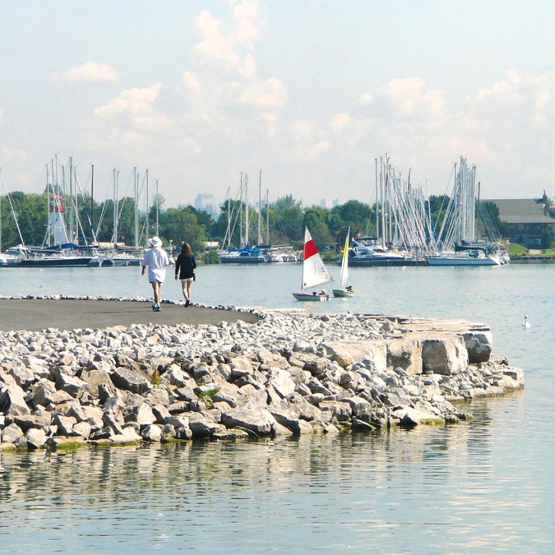 a waterfront trail with pebble shoreline and boats in the lake