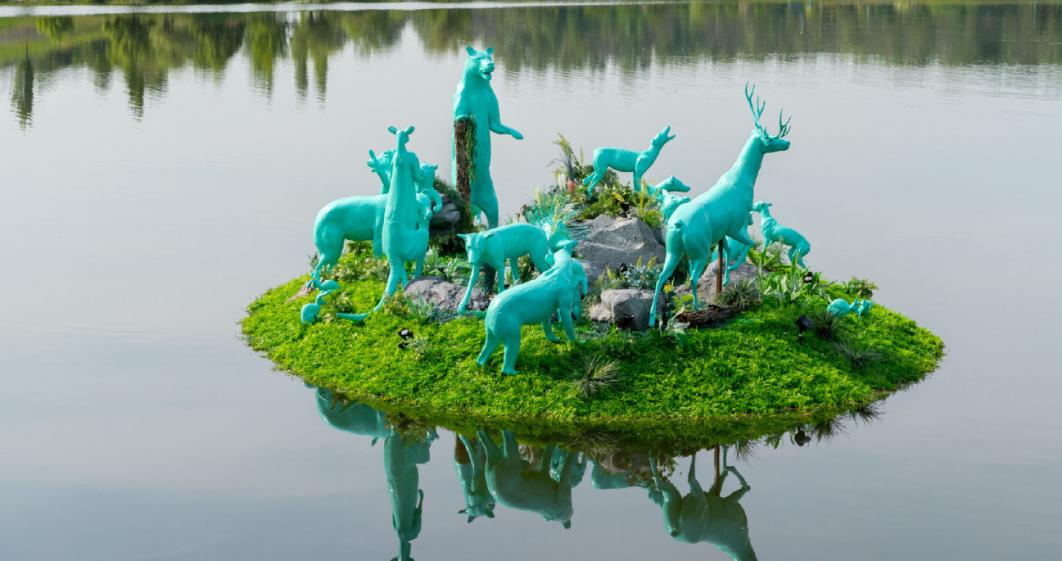 Art installation with model animals all painted blue on a floating island.