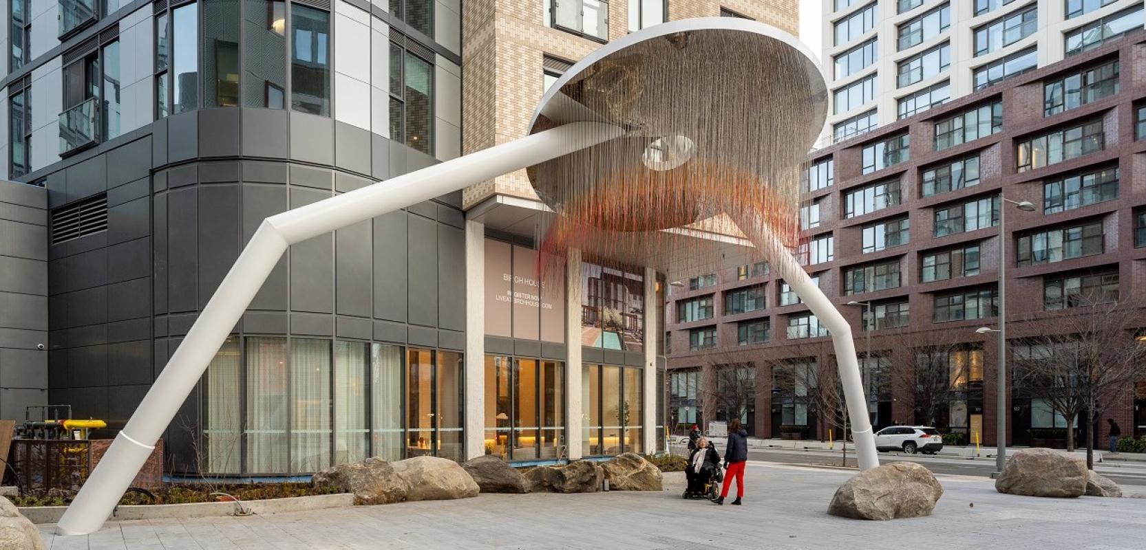 A circular art piece with two legs stands at the entry of a building. 