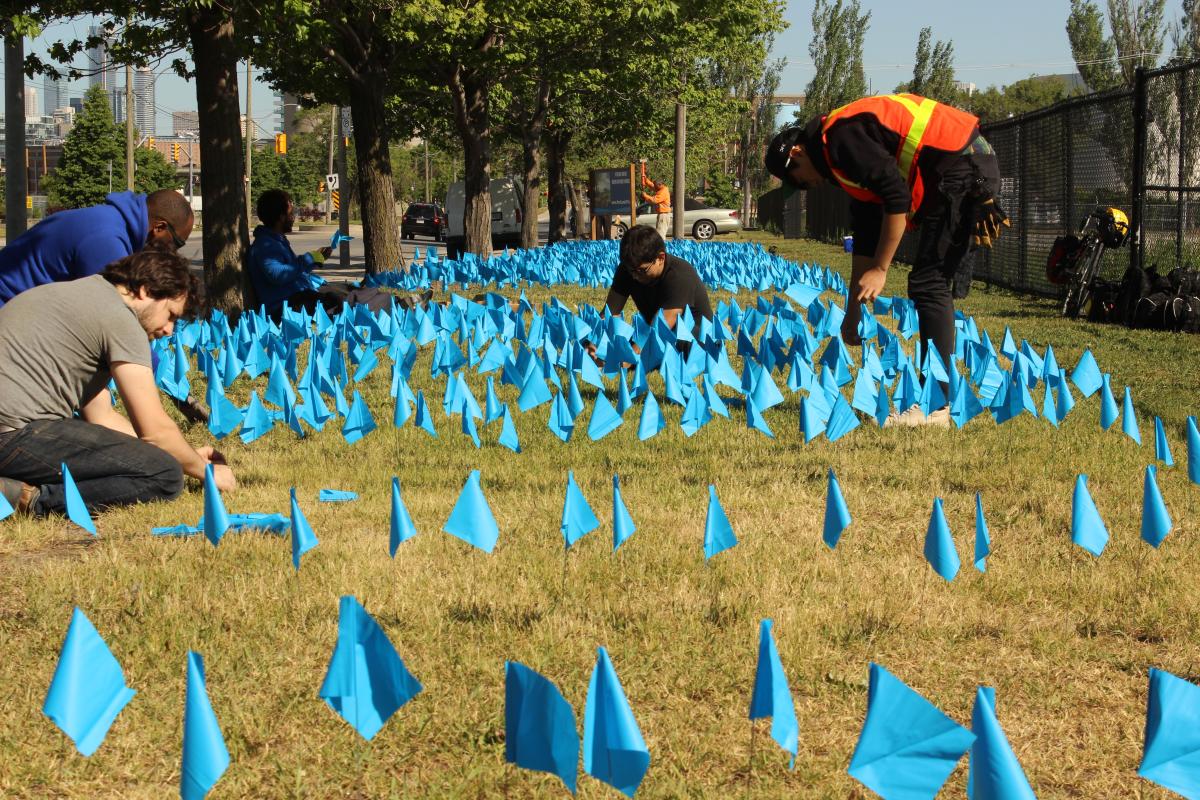 a series of small blue flags displayed on a grassy area