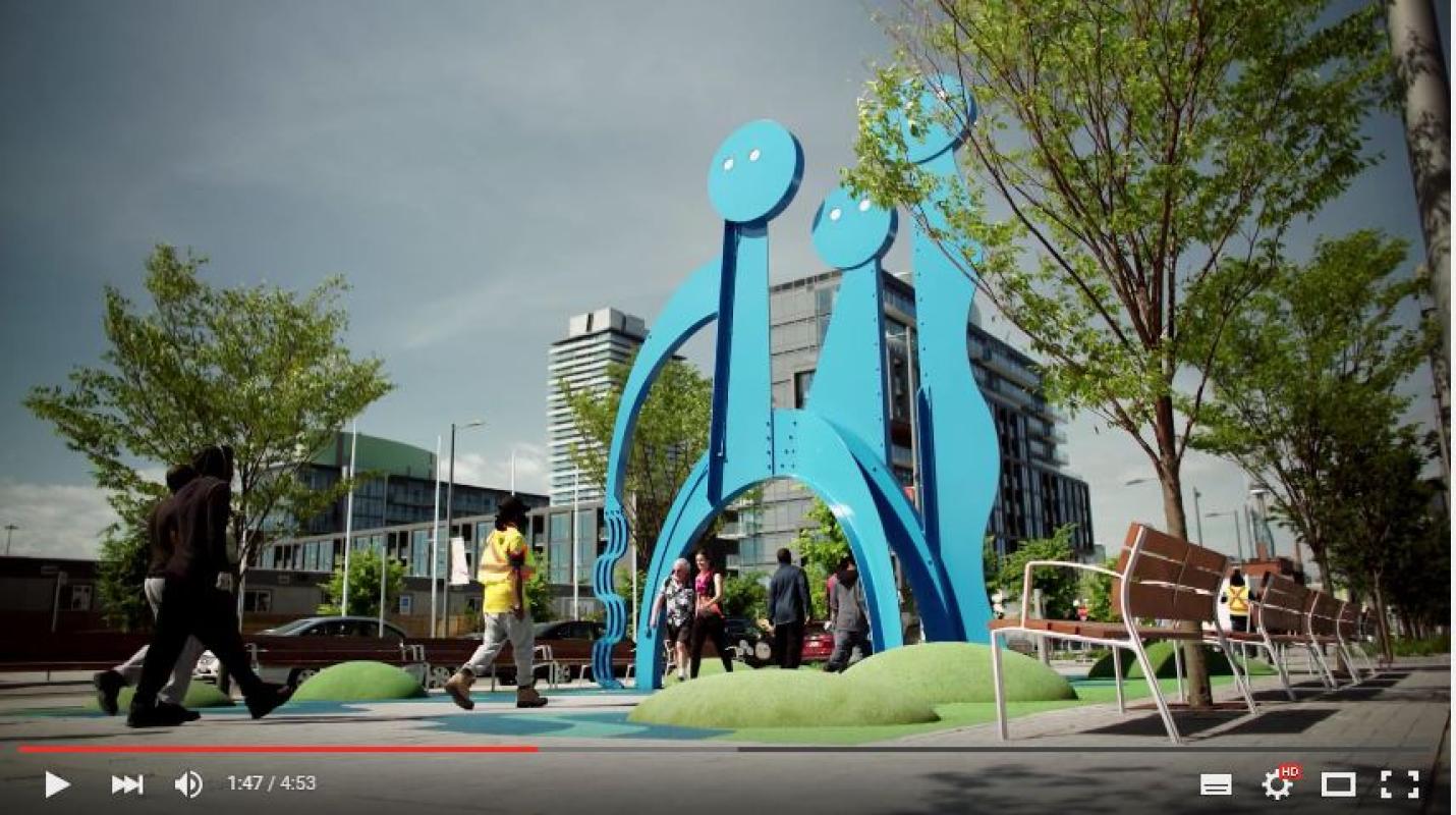 screenshot of video showing a public art installation of large blue figures