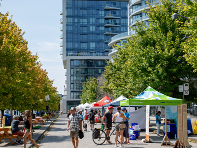 People enjoy a market along a promenade on the waterfront.