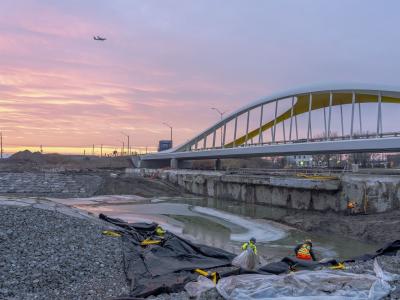 A concrete wall next to a bridge separating a new river valley from the lake