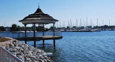 a gazebo on the waterfront with a marina in the background