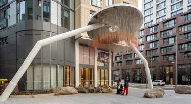 A circular art piece with two legs stands at the entry of a building.