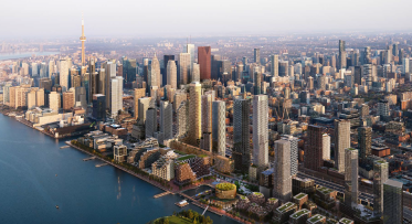 The skyline of Toronto, with Lake Ontario in the foreground and dense downtown buildings beyond.