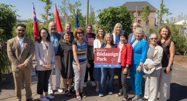 Group photo from the official opening of a new park. One dignitary holds a sign saying "Welcome to Biidaasige Park".